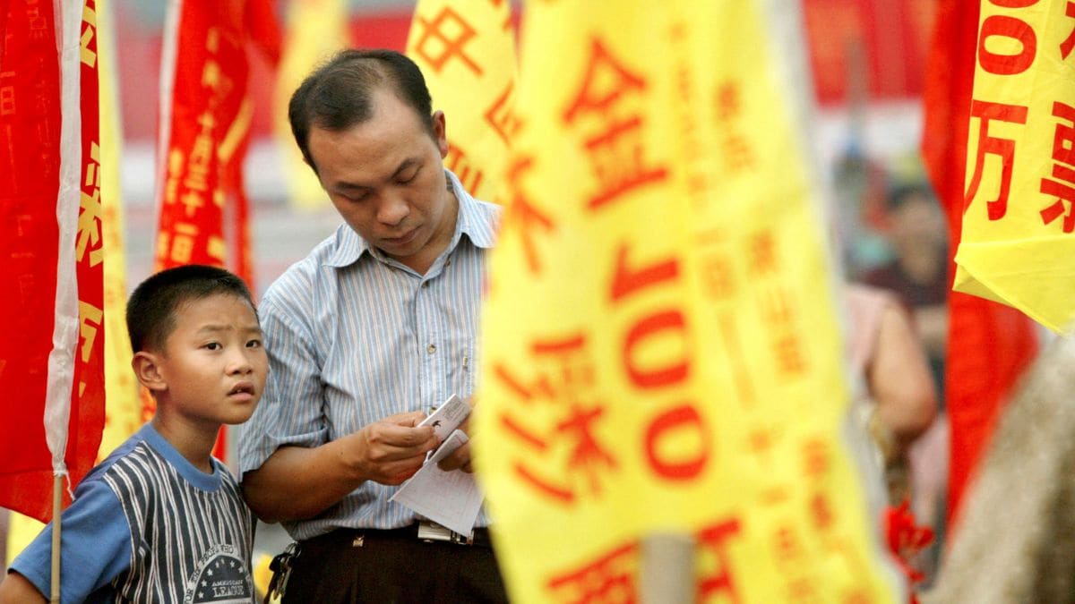 2003 年 11 月 1 日，一名中国男子和他的儿子在中国南方城市广州的一场晚会上检查他们的彩票。资料图片/路透社